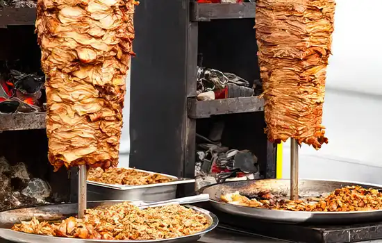 Image of shawarma on large rotating spits being cooked using traditional Middle Eastern methods.